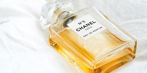 A Chanel No. 5 bottle on a white bedsheet A Chanel No. 5 bottle on a white bedsheet